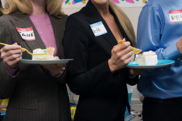 Three office workers eating cake