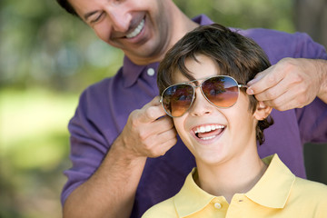 Father putting sunglasses on son