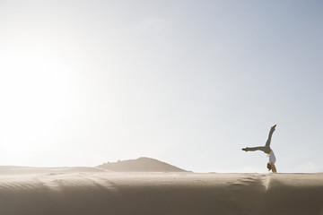 Woman doing handstand in desert