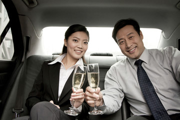 business people toasting champagne back of car