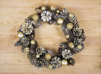 Christmas wreath of cones and balls on wooden surface.