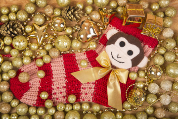 Christmas background with gold balls and monkey on red sock.