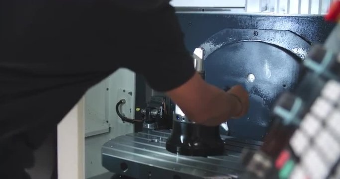 Male Engineer Operating CNC Machinery On Factory Floor