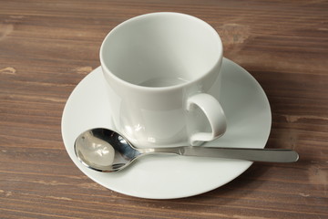 Empty white cup and saucer on wooden background