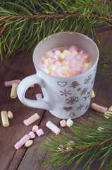 Obraz na płótnie Canvas Hot cocoa in a gray cup with marshmallows under christmas tree