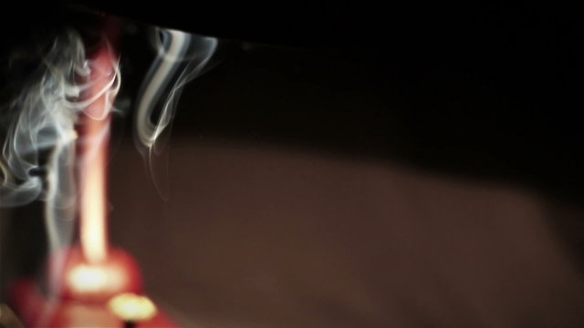 A smoke hovering in the air in the light of a table-lamp