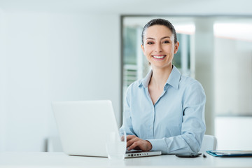 Smiling young businesswoman working at office desk