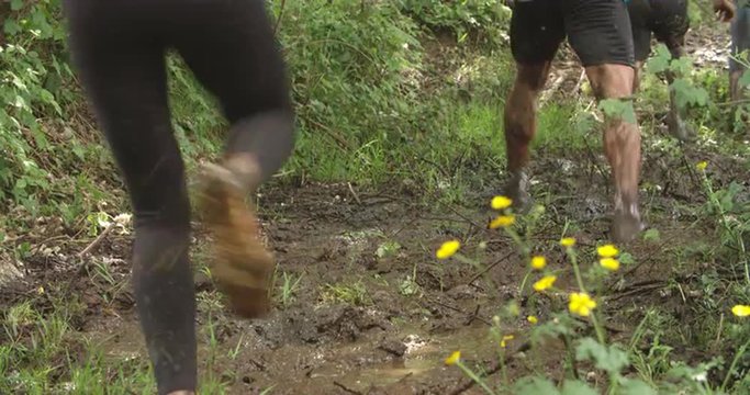 Legs of competitors running through mud on an assault course