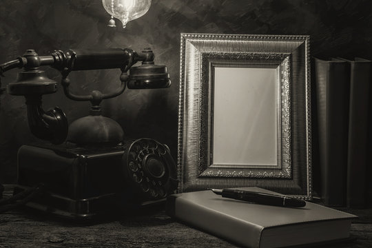 Still life of vintage telephone with picture frame and diary on