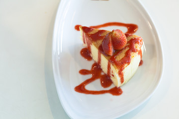Strawberry Cheesecake decorated with red sweet sauce in the whit