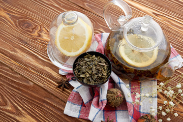 Ripe lemon, cinnamon and fruit drink in glass teapot on wooden background