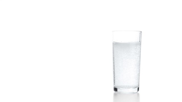 Sparkling water in glass. Bubbles rising up and exploding