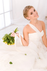 Obraz na płótnie Canvas Smiling bride holding flowers