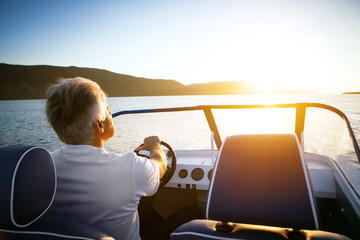mature man driving speedboat - Powered by Adobe
