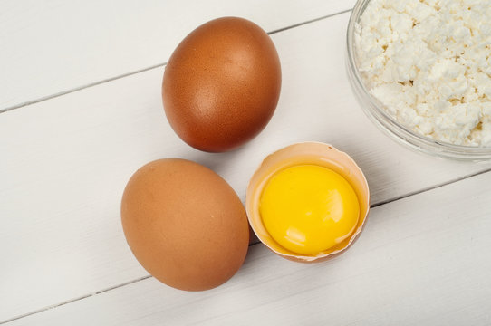 Whole and broken raw brown eggs with cottage cheese