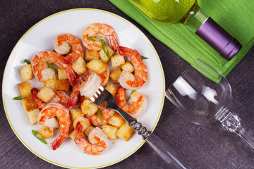 Shrimp with crispy croutons and scallions;  white wine bottle. View from above, top studio shot