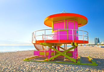 Sunrise in Miami Beach Florida, with a colorful pink  lifeguard house in a typical Art Deco architecture, at sunrise with ocean and sky in the background. - 97102212