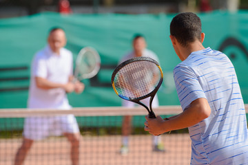 Men playing doubles game of tennis