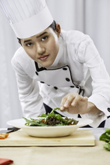 portrait of female chef patiently placing salad on a plate
