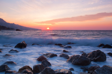 A beautiful sunrise over the sea, in the foreground large stones