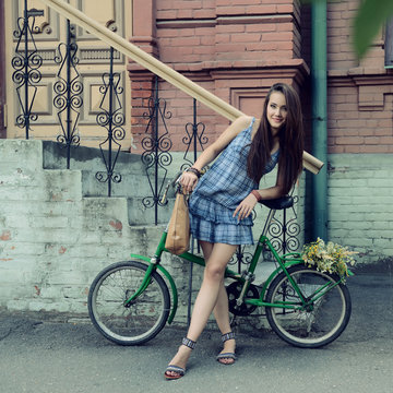 Street portrait of young beautiful woman with bicycle, image ton