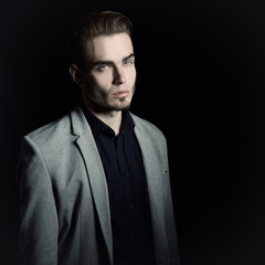 Portrait of attractive mysterious young man over black backgroun