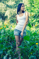 Naklejka na ściany i meble Beauty Sporty Girl Outdoors. Beautiful Teenage Model girl Dressed in Casual Denim Shorts in the Field Tond Image. Twisted body. Toned in cool color