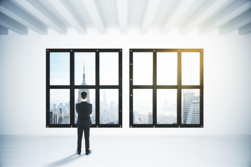Businessman in empty white loft style room with city view