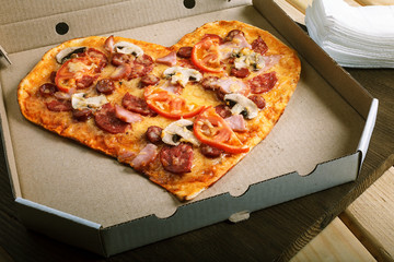 Pizza heart shape on dark wooden background top view