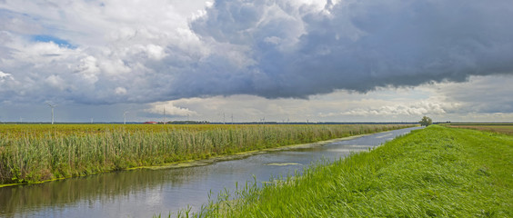 Clouds over a canal through a rural landscape 