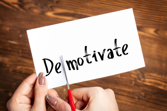Woman hands cutting card with the word demotivate