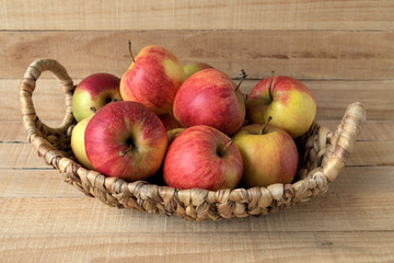 Apples. Red ripe apples in a basket on a light wooden surface.