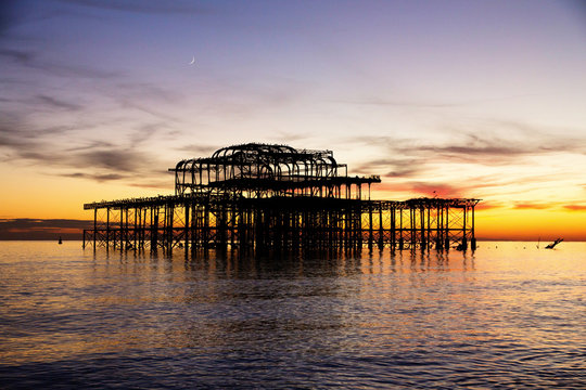 Remains of Brighton Pier left standing in sea at sunset,