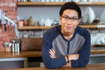 Confident handsome man standing in cafe with arms crossed