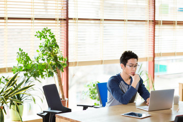 Concentrated asian man working with laptop in office