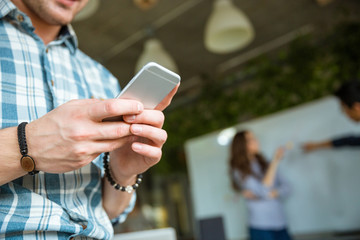 Hands of man using mobile phone while his partners arguing