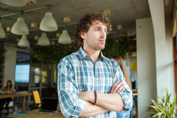 Thoughtful man standing in office with folded hands