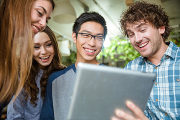 Fototapeta premium Cheerful young people laughing and using tablet