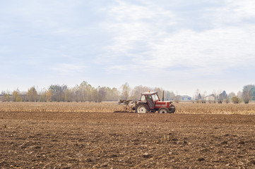 Obraz premium Red Tractor Plowing in Autumn