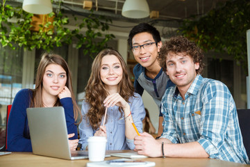 Group of happy young students sitting at the table