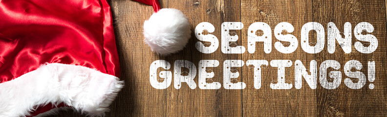 Seasons Greetings! written on wooden with Santa Hat © gustavofrazao