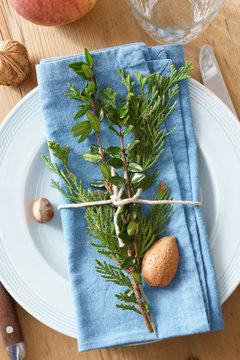 Place setting decor with evergreen plants, nuts and apple