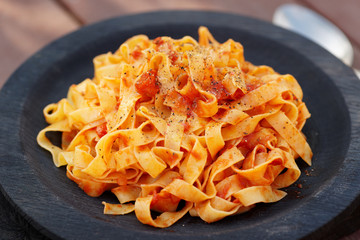 Tagliatelle with tomato sauce in wooden plate