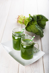 Bebida green smoothie o batido verde energético con frutas hojas de espinacas y verduras para una dieta sana en mason jar con pajita en espiral