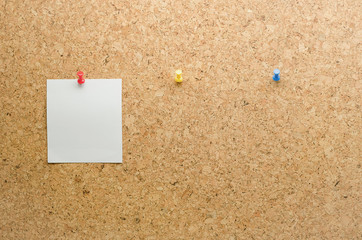 Paper card posted on a cork board with tack pin and waiting pape