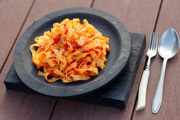 Tagliatelle with tomato sauce in wooden plate