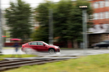 red car rides in the rain on a city