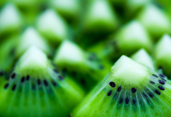 Couple of green kiwi slices, with more blurred slices in the background