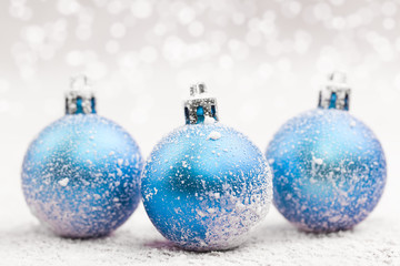 Christmas ball in the snow on blurred light background. A holiday card. Traditional Christmas decorations.