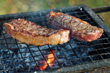 Two pieces of striploin steak on  grill